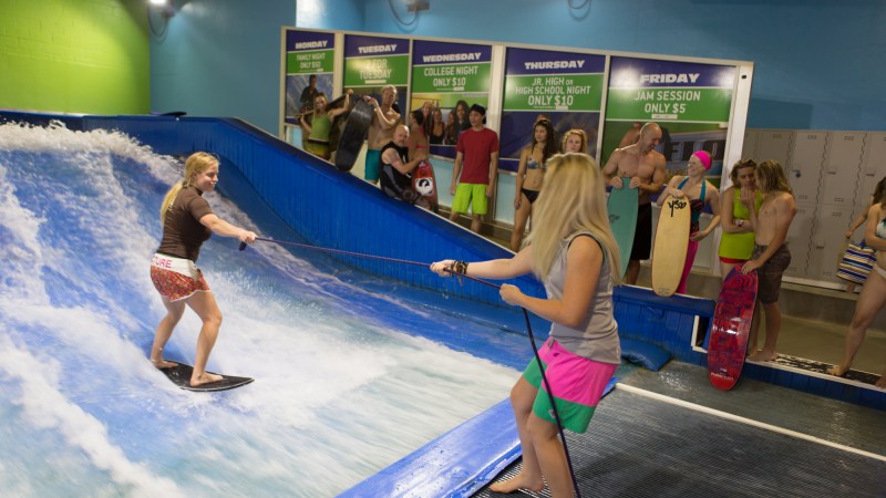 an employee helping a girl flowboard